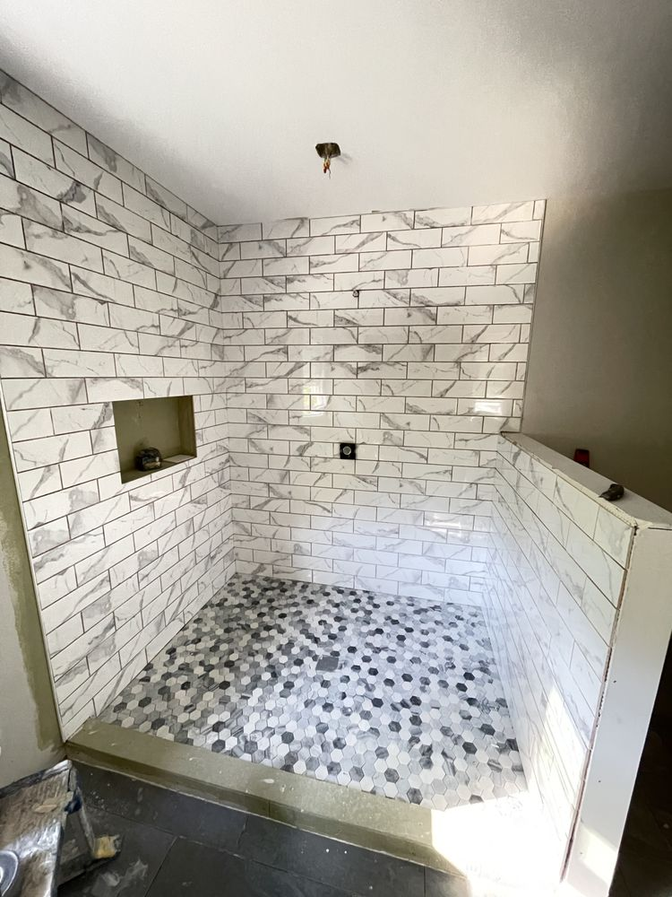 Walk-in shower with white subway tile walls and hexagonal mosaic floor tile