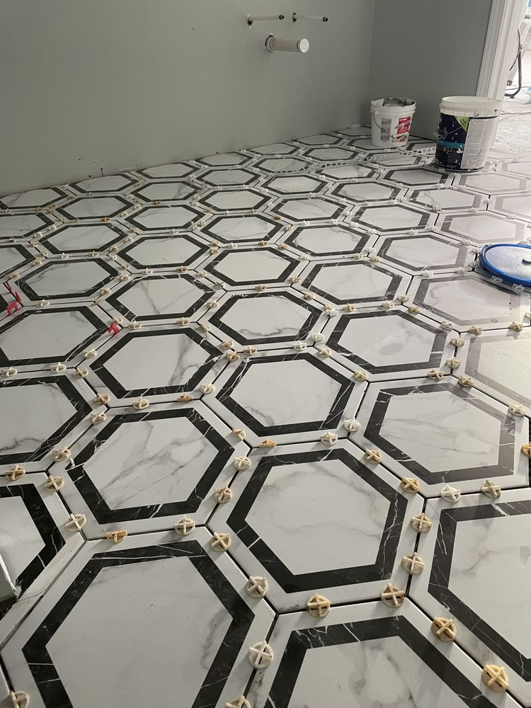 Geometric hexagon tile floor installation in progress with black grout lines and spacers