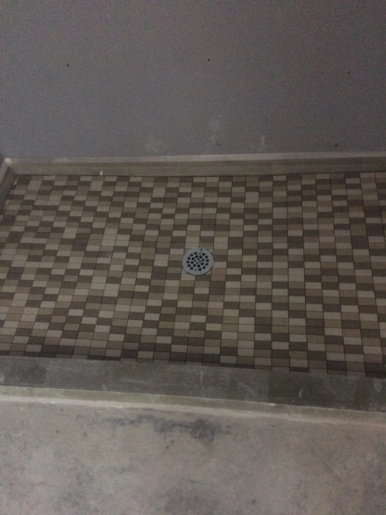 Shower floor with brown and tan checkered tile pattern and central drain